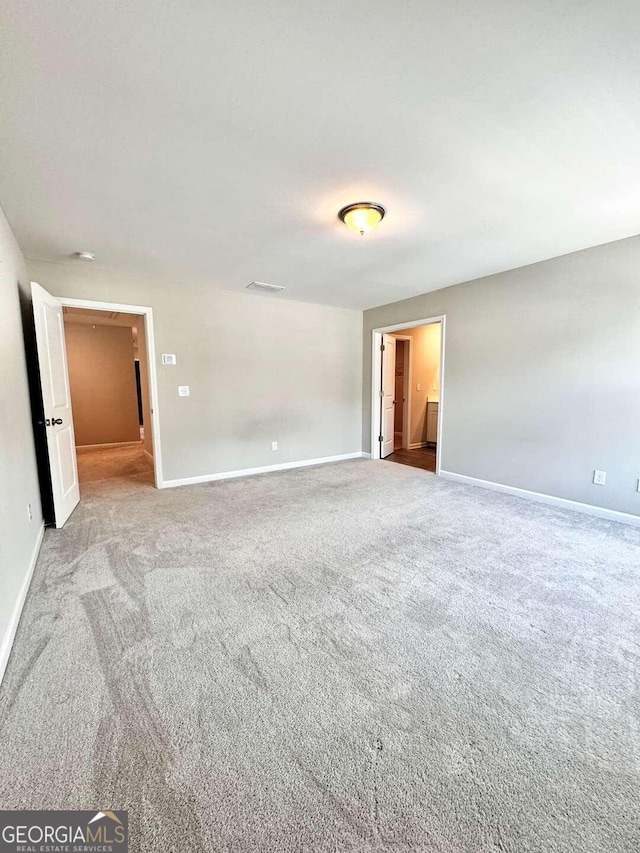 unfurnished bedroom with light colored carpet and connected bathroom