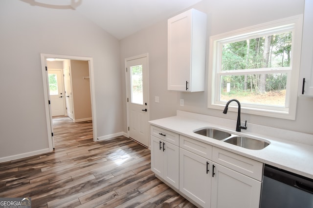 kitchen with stainless steel dishwasher, hardwood / wood-style floors, and white cabinets