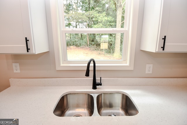 room details with light stone counters, white cabinetry, and sink