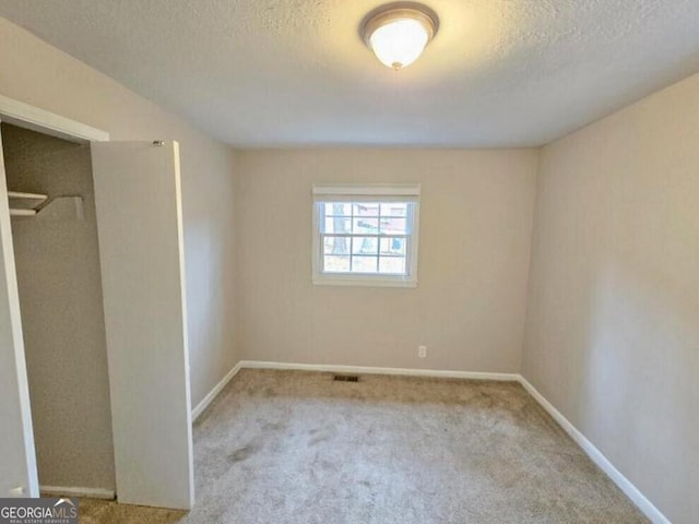 unfurnished bedroom with a textured ceiling and light carpet