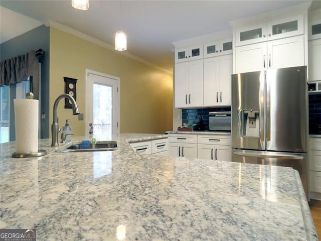 kitchen with light stone counters, stainless steel fridge, and white cabinets