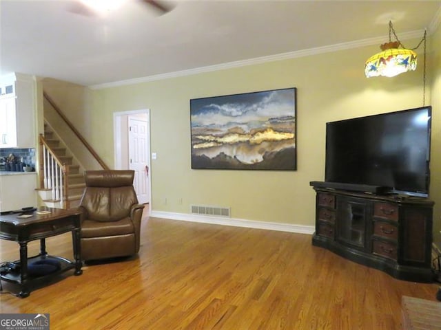 living room featuring crown molding, hardwood / wood-style flooring, and ceiling fan