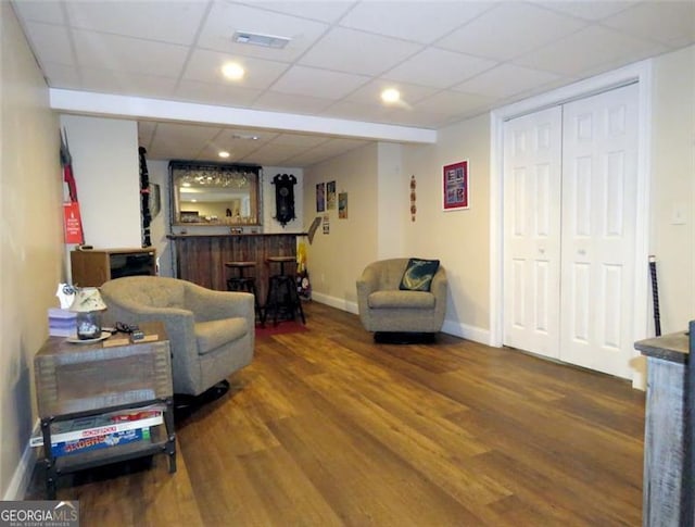 living room featuring hardwood / wood-style floors, a drop ceiling, and bar