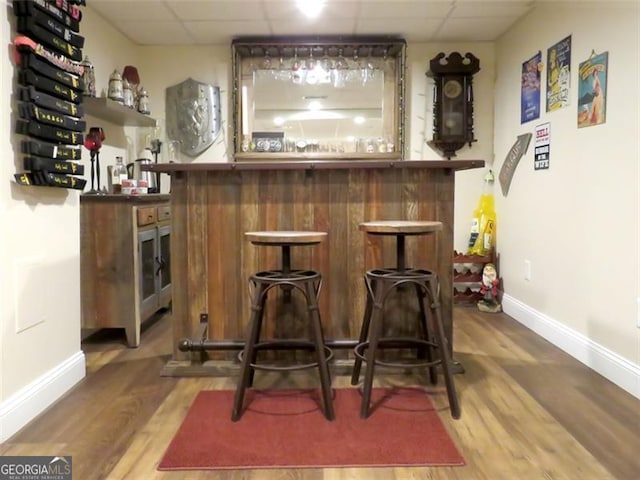 bar with hardwood / wood-style flooring and a paneled ceiling