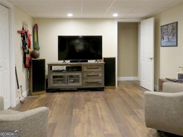 living room with a drop ceiling and wood-type flooring