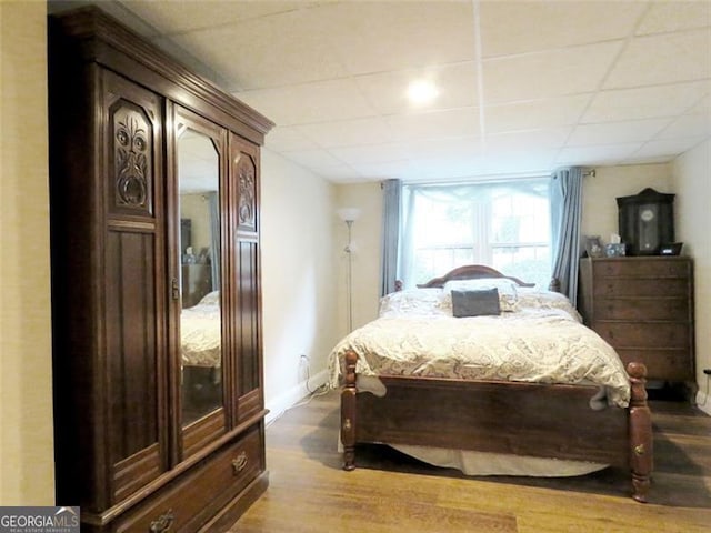 bedroom with a paneled ceiling and hardwood / wood-style flooring