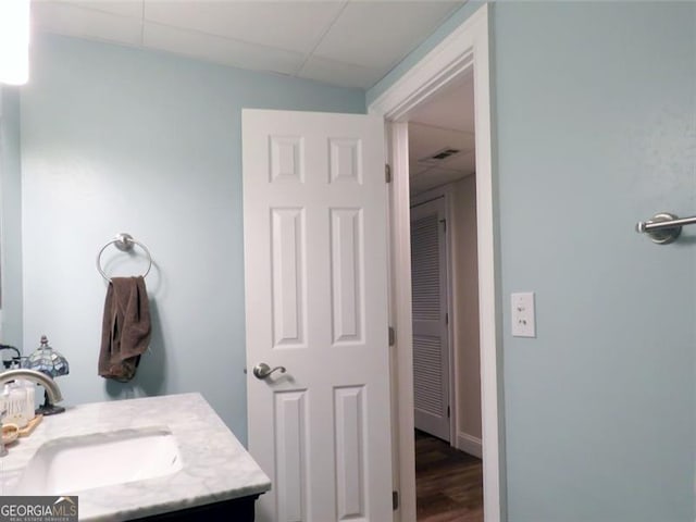 bathroom with vanity, a paneled ceiling, and hardwood / wood-style floors