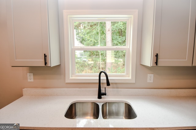 kitchen featuring a wealth of natural light, light stone counters, and white cabinetry