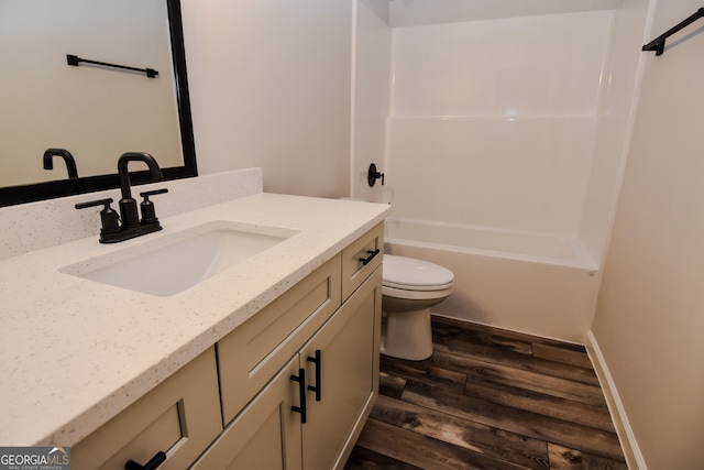 full bathroom with hardwood / wood-style floors, toilet,  shower combination, and vanity