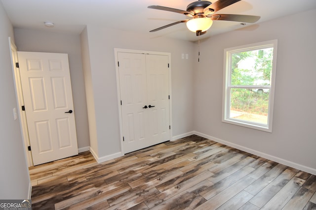 unfurnished bedroom with wood-type flooring, ceiling fan, and a closet