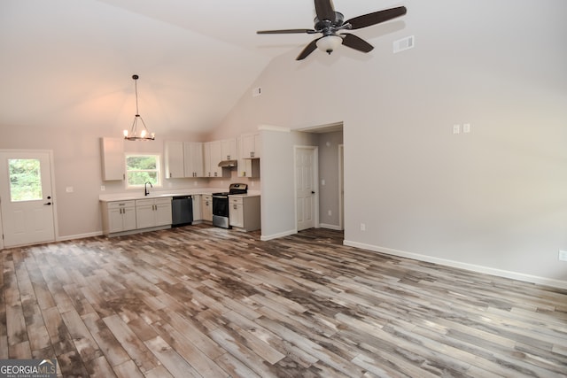 unfurnished living room with ceiling fan with notable chandelier, high vaulted ceiling, and light hardwood / wood-style flooring