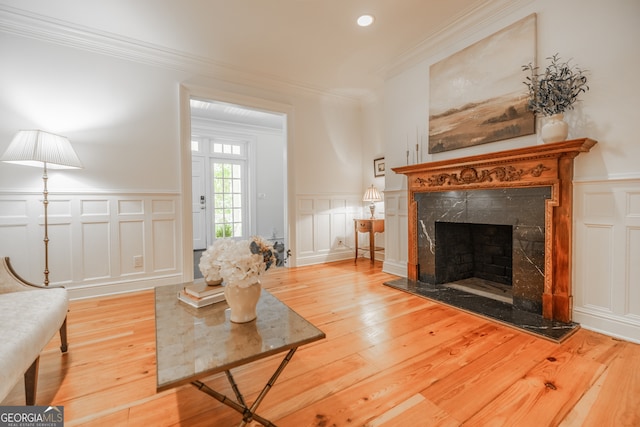 living room with hardwood / wood-style flooring, ornamental molding, and a premium fireplace