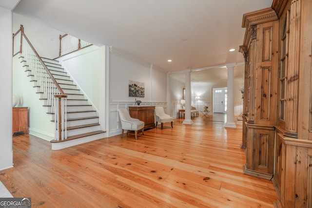 foyer with crown molding, light hardwood / wood-style flooring, and decorative columns