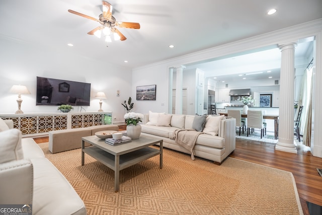 living room featuring light wood-type flooring, ceiling fan, decorative columns, and ornamental molding