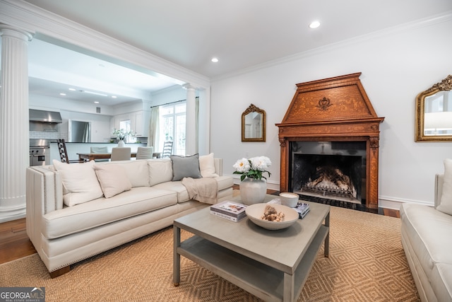 living room with decorative columns, crown molding, and light hardwood / wood-style flooring