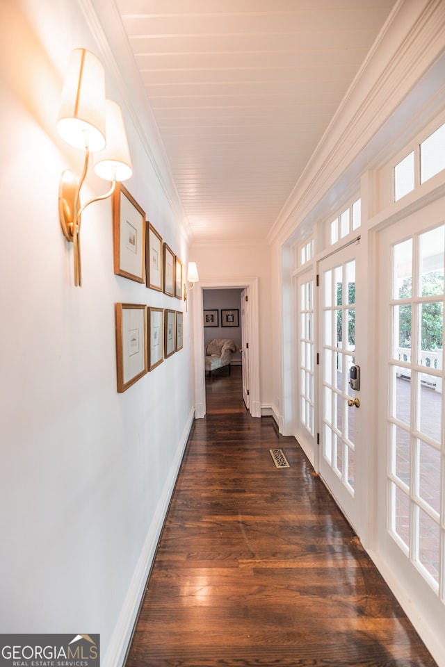 corridor with dark wood-type flooring, ornamental molding, a notable chandelier, and french doors