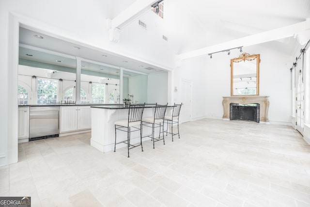 kitchen with a high end fireplace, a barn door, beamed ceiling, white cabinetry, and stainless steel dishwasher