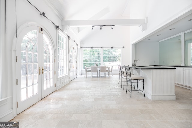 kitchen featuring a breakfast bar area, a wealth of natural light, white cabinetry, and french doors