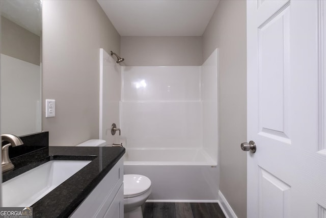 full bathroom featuring washtub / shower combination, hardwood / wood-style floors, toilet, and vanity