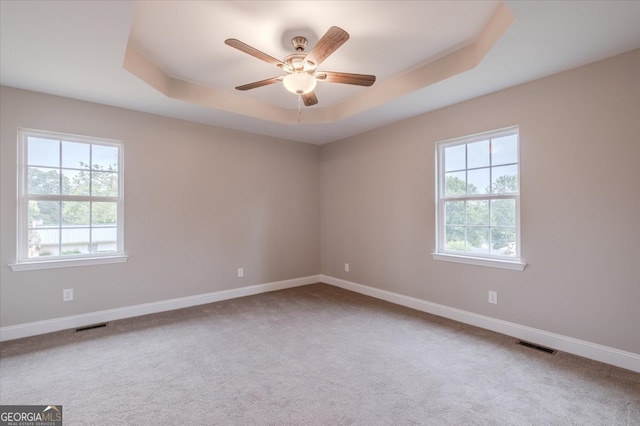 empty room with carpet, ceiling fan, and a tray ceiling