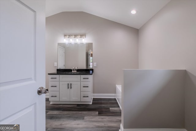 bathroom with lofted ceiling, a washtub, hardwood / wood-style flooring, and vanity