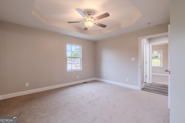 carpeted spare room featuring a tray ceiling and ceiling fan