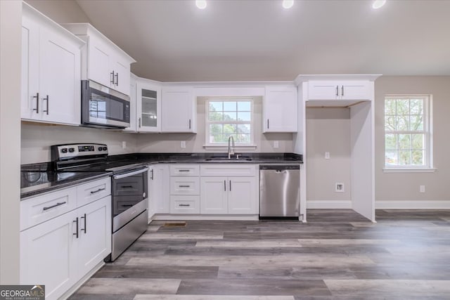 kitchen with stainless steel appliances, sink, hardwood / wood-style floors, and white cabinets