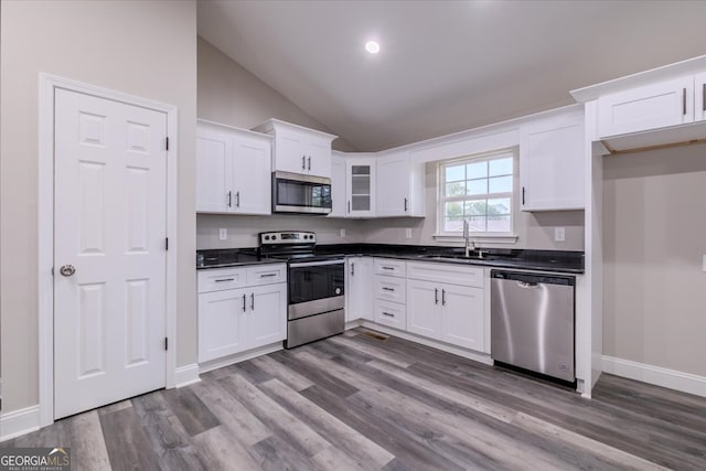 kitchen featuring high vaulted ceiling, white cabinetry, stainless steel appliances, sink, and hardwood / wood-style flooring