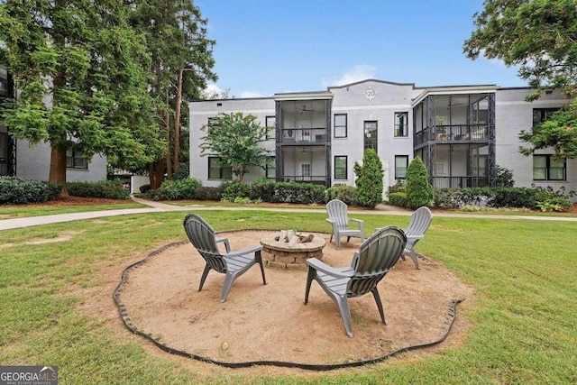 view of property's community featuring a lawn, a patio area, and an outdoor fire pit