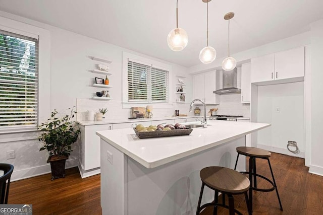 kitchen with a kitchen island with sink, wall chimney exhaust hood, white cabinets, and dark hardwood / wood-style floors