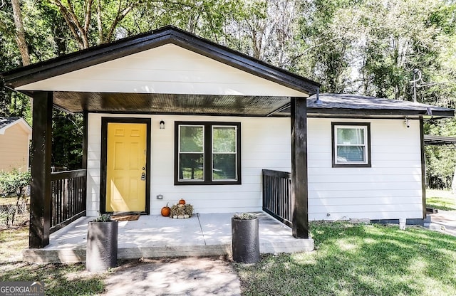 rear view of property with covered porch and a yard