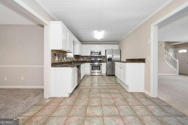 kitchen featuring decorative backsplash, stainless steel appliances, white cabinets, and light colored carpet