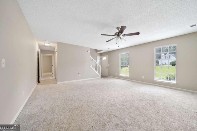 spare room featuring light carpet, ceiling fan, and a textured ceiling