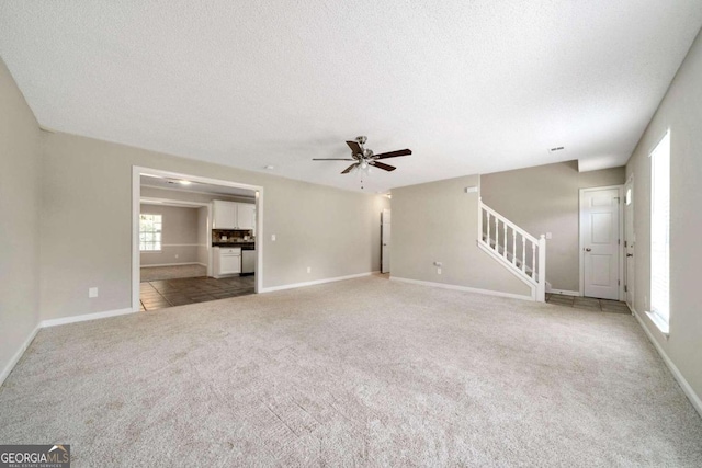 unfurnished living room with carpet, ceiling fan, and a textured ceiling