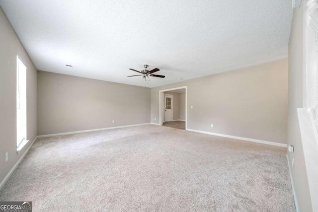 spare room with ceiling fan, a textured ceiling, and light carpet