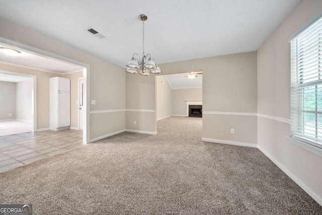 carpeted empty room with an inviting chandelier and a textured ceiling