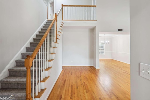 stairs with hardwood / wood-style flooring and a chandelier