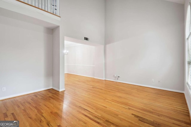 empty room featuring light hardwood / wood-style flooring, a high ceiling, and a wealth of natural light