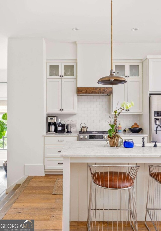 kitchen with light hardwood / wood-style floors, a breakfast bar area, white cabinetry, and tasteful backsplash