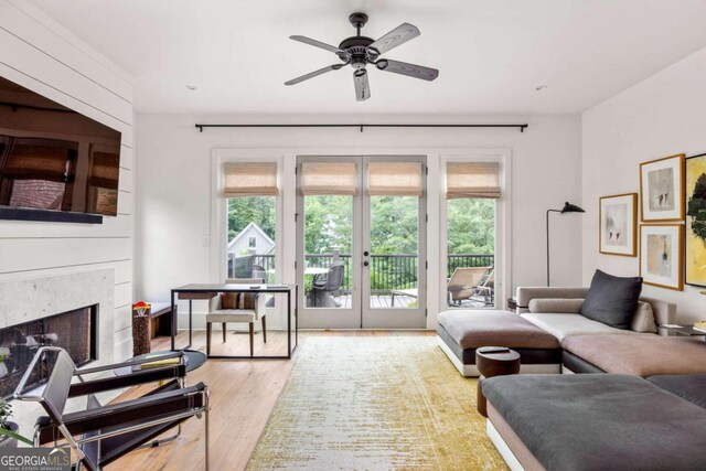 living room featuring a premium fireplace, ceiling fan, and light hardwood / wood-style flooring