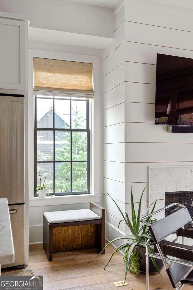 room details with wood walls, hardwood / wood-style flooring, stainless steel fridge, and a high end fireplace