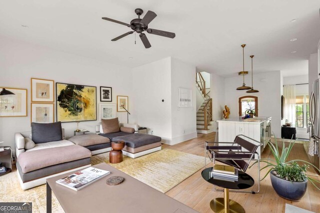 living room featuring ceiling fan, sink, and light wood-type flooring