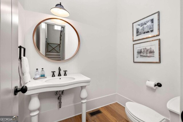 bathroom with toilet, sink, and hardwood / wood-style flooring