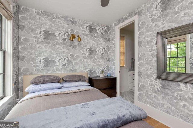 bedroom with hardwood / wood-style floors, ensuite bath, and ceiling fan