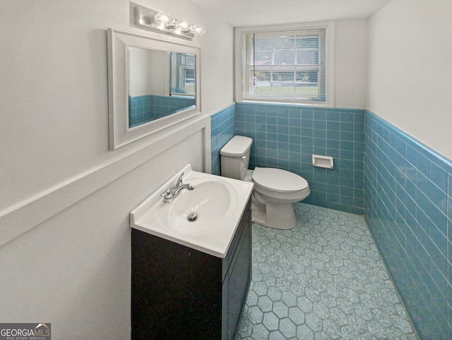 bathroom featuring vanity, toilet, tile walls, and tile patterned floors