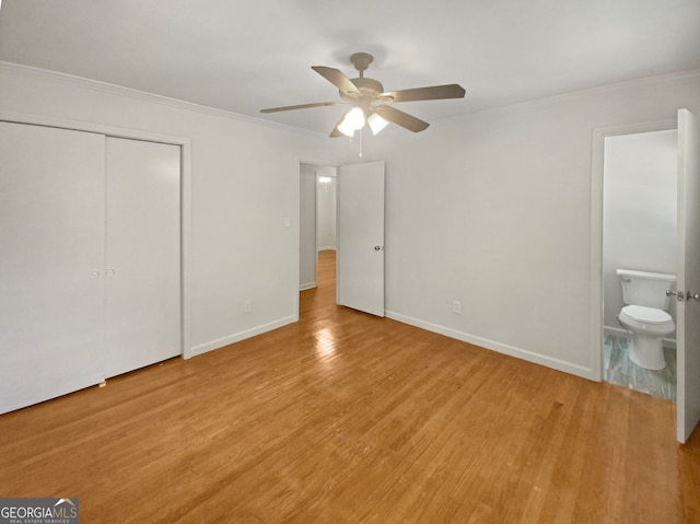 unfurnished bedroom featuring light wood-type flooring, a closet, ceiling fan, and ensuite bathroom