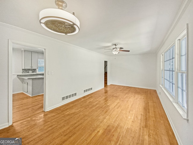 unfurnished living room with ceiling fan, a wealth of natural light, ornamental molding, and light hardwood / wood-style flooring