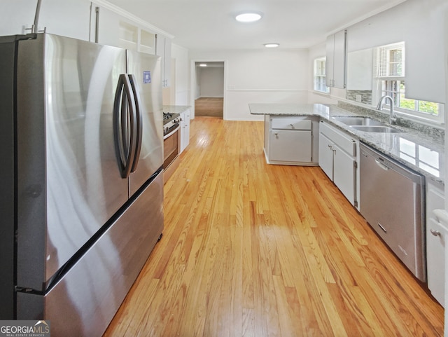 kitchen featuring light wood-type flooring, appliances with stainless steel finishes, white cabinetry, and sink