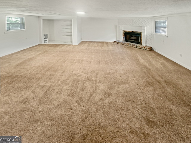 unfurnished living room featuring a textured ceiling, a brick fireplace, and carpet floors