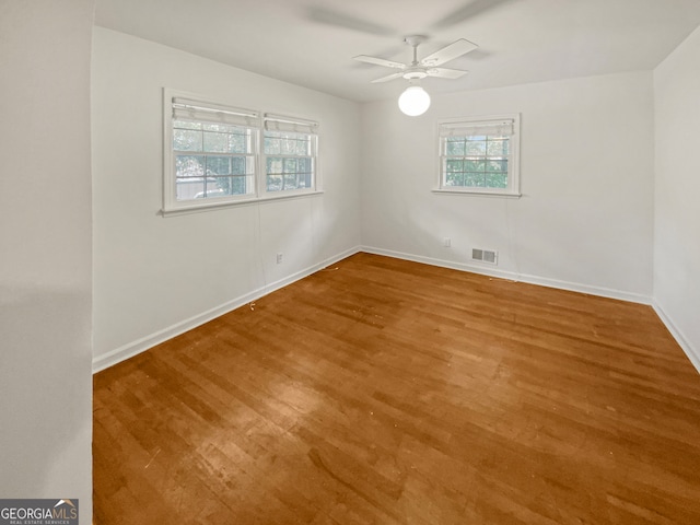 unfurnished room featuring a healthy amount of sunlight, ceiling fan, and hardwood / wood-style flooring